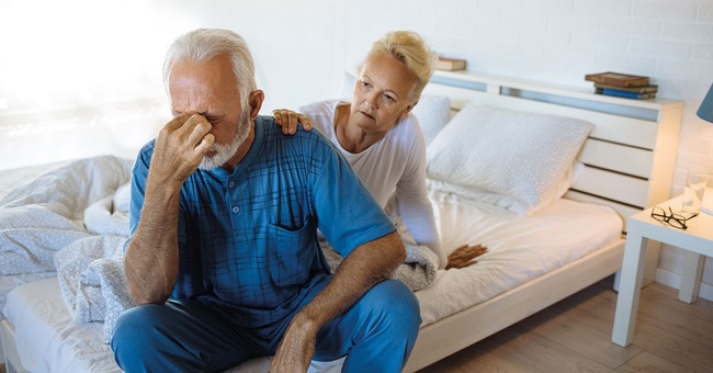 Mann verzweifelt an seinen Schmerzen, Frau legt ihm die Hand auf die Schulter © iStock