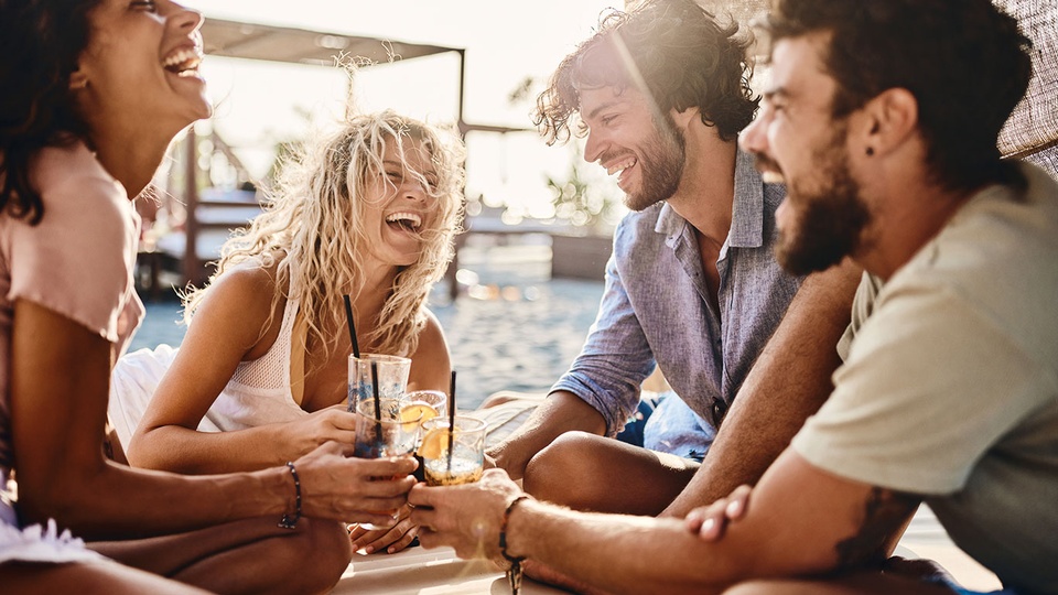 Freunde lachen und trinken gemeinsam. © iStock